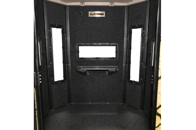 Muddy Elevated hunting box blind made of steel, showcasing a large deer stand with a ladder and a cracked mud camouflage design.