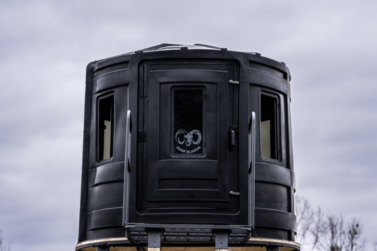 A deer hunting blind with a ladder, suitable for hunting, showcasing RAM 650 acrylic windows for both bow and gun enthusiasts.