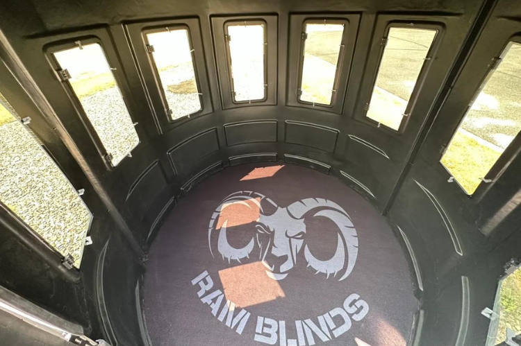 A deer hunting blind with a ladder, suitable for hunting, showcasing RAM 650 acrylic windows for both bow and gun enthusiasts.